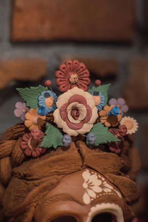 Flowers made of clay on a catrina mask of the same material, painted in various tones and colors.
