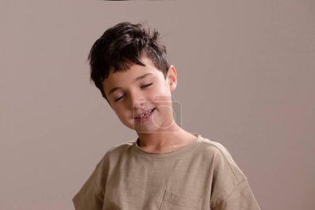 Téléchargez les photos : Heureux caucasien brunette garçon avec fermé les yeux debout sur studio fond - en image libre de droit