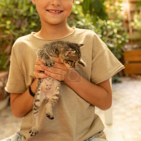 Téléchargez les photos : Joyeux enfant joue avec un petit chaton à l'extérieur. Le concept d'animaux domestiques, amis, gentillesse, soins des chats, hygiène, propreté des mains, vers. Lumière du jour. - en image libre de droit