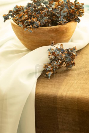 Photo for Dry petals of blue hydrangea inflorescence in a wooden bowl standing on the table. White background. Home decor, dried flowers, natural colors concept. Nobody. Copy space. - Royalty Free Image
