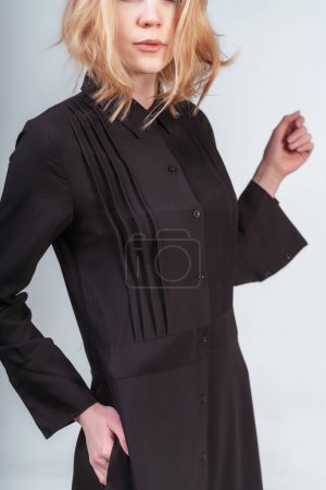 Téléchargez les photos : Portrait d'une fille russe en robe noire sur fond blanc. séance photo de vêtements noirs sur un fond clair. fille blonde en robe de coton noir - en image libre de droit