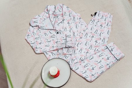 Photo for Nightgown with flamingo pattern on the bed. photo session of silk women's sleepwear. women's colored pajamas - Royalty Free Image