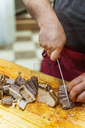 Téléchargez les photos : Trancher de la viande de bœuf pour beshparmak kazakh. Préparation de viande de cheval par les mains du chef pour des plats chauds. Couper de gros morceaux de viande en petites tranches - en image libre de droit