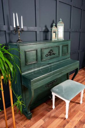 Foto de Un piano verde oscuro con una silla ligera contra una pared azul oscuro. una decoración ya hecha para una sesión de fotos de boda. un piano de color real en una habitación espaciosa - Imagen libre de derechos