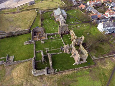 Foto de Aerial view of the medieval ruins of Lindisfarne Priory on Holy Island off the coast of Northumberland in northeast England. - Imagen libre de derechos
