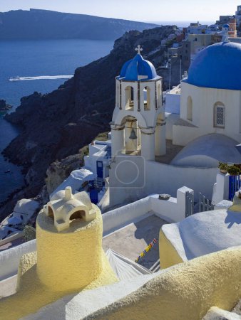Foto de Campanario e iglesia abovedada azul en lo alto del borde de la caldera volcánica en la isla griega de Santorini (Thira) en el mar Egeo meridional. - Imagen libre de derechos