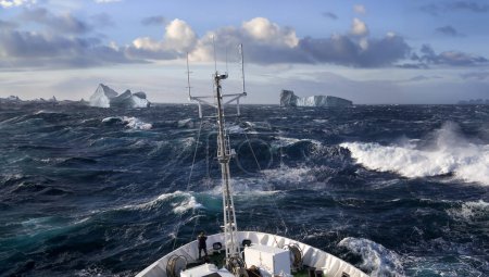 Barco que rueda en mares pesados cerca de icebergs en Scoresbysund en la costa este de Groenlandia.