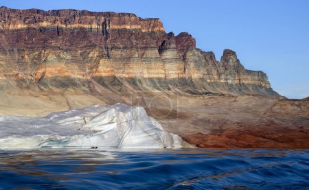 Foto de Turistas de aventura cerca de un iceberg bajo las rocas sedimentarias del fiordo Franz Joseph en el este de Groenlandia. - Imagen libre de derechos