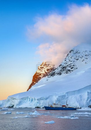 Téléchargez les photos : Lumière du soleil de minuit et brise-glace touristique dans le chenal Lamaire sur la péninsule Antarctique en Antarctique. - en image libre de droit
