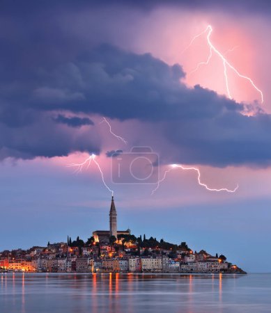 Foto de Rayo y nubes de tormenta sobre la ciudad de Ravinj en la península de Istria en Croacia. La ciudad también es conocida por su nombre italiano de Rovigno. - Imagen libre de derechos