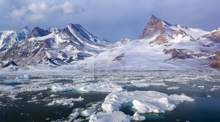 Téléchargez les photos : Montagnes côtières reculées et glace de mer sur la côte est du Groenland - en image libre de droit