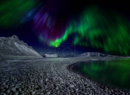Polarlichter über den Bergen an der Küste Islands. Polarlichter (Nord- und Südlichter) sind natürliche Lichtspiele am Himmel, insbesondere in den Polarregionen. Sie treten in der Ionosphäre auf. 