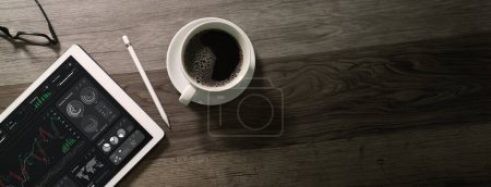 Photo for Top view Cup of coffee with digital tablet computer, business finance charts and pen on wood background. - Royalty Free Image