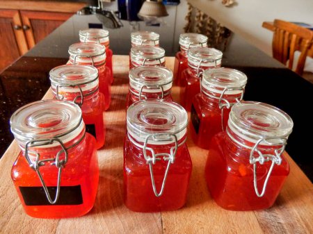 Foto de Pequeños frascos de salsa casera de chile dulce hechos de chiles orgánicos cultivados en casa. A veces llamado mermelada de chile - Imagen libre de derechos