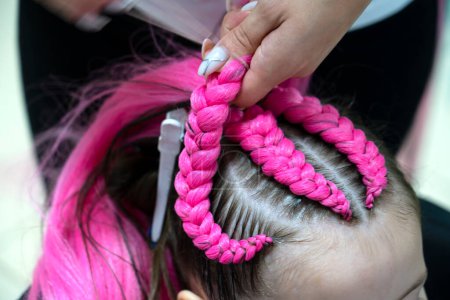 Foto de El proceso de trenzado trenzas de moda de color rosa brillante y azul kanekalon para una niña. De vuelta a la escuela. Estudio de trenzas. Foto de alta calidad - Imagen libre de derechos