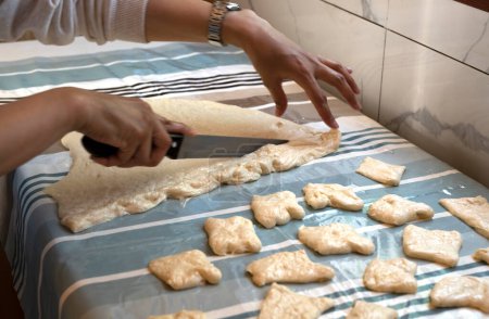 Photo for Preparation of traditional Kazakh pastries - baursaks. The woman cuts the dough into pieces. High quality photo - Royalty Free Image