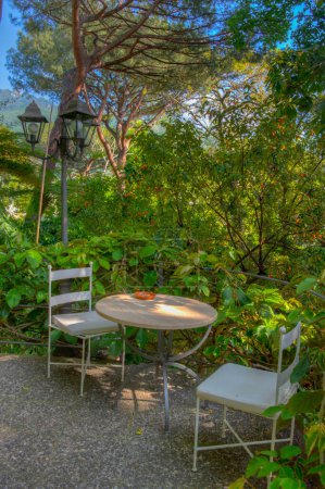 Téléchargez les photos : Chaise et table dans les jardins Giardini la Mortella à Ischia, Italie. - en image libre de droit