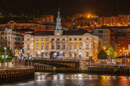 Foto de Bilbao, España, 2 de junio de 2022: Vista nocturna del paseo marítimo del río Nervión cerca del ayuntamiento de Bilbao, España. - Imagen libre de derechos