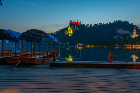Vista del atardecer sobre los botes de remos que miran el castillo de Bled en Eslovenia