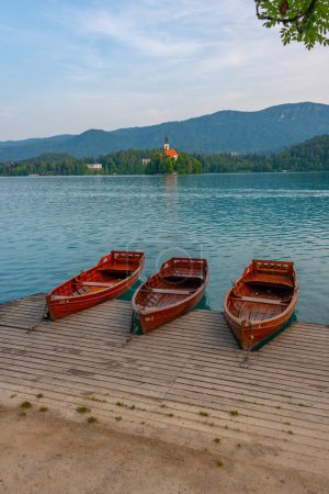 Rowing boat at shore of lake Bled with Assumption of Maria church at background, Slovenia