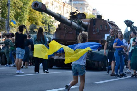 Téléchargez les photos : Une fille avec un drapeau ukrainien passe devant un véhicule blindé russe détruit exposé sur la rue Khreshchatyk le jour de l'indépendance de l'Ukraine, le 24 août 2023 à Kiev, en Ukraine. - en image libre de droit