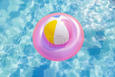 Inflatable pool with swimming ring and rings in a water on blue background in the summer day.