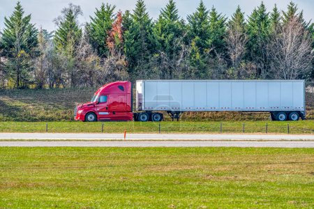 Téléchargez les photos : Plan horizontal d'une remorque tracteur rouge voyageant sur une autoroute solitaire de la fin de l'été. - en image libre de droit