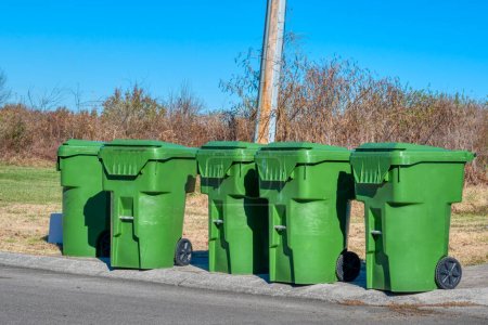 Foto de Cinco contenedores de basura residenciales verdes por calle de la ciudad. - Imagen libre de derechos