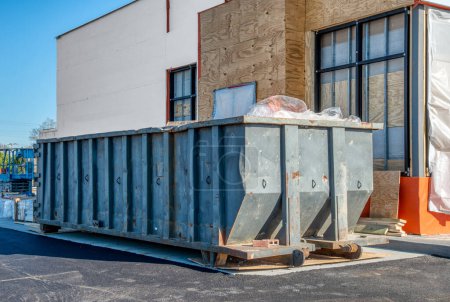 Ein großer, schwerer Müllcontainer neben einem neuen Fast-Food-Restaurant im Bau.