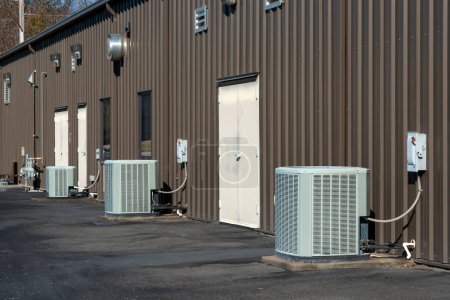 A row of generic air conditioner compressors behind a strip office building