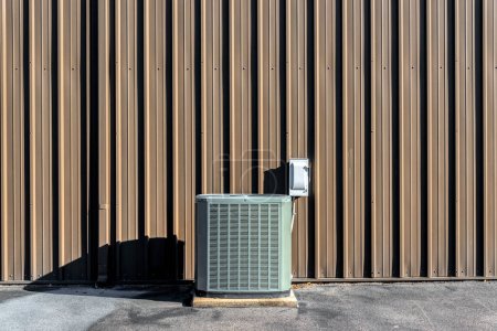 Photo for A horizontal image of an A/C compressor in front of a blank brown wall with copy space. - Royalty Free Image