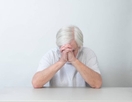 Photo for Horizontal shot of a white haired man sitting alone in sadness, prayer or worry.  White background.  Lots of copy space. - Royalty Free Image