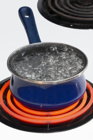 Foto de Vertical shot of a blue pot on a stove top on a red hot burner holding boiling water.  Copy space. - Imagen libre de derechos
