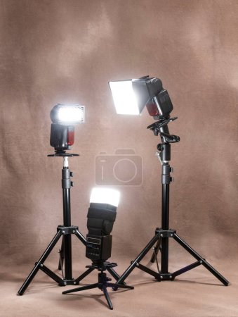 Photo for Vertical shot of three radio-controlled electronic strobes on tripods firing in unison on a canvas background. - Royalty Free Image