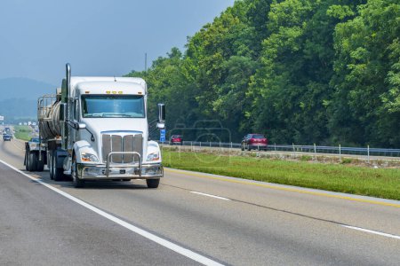 Horizontal shot of a white tanker truck on an interstate highway with copy space.