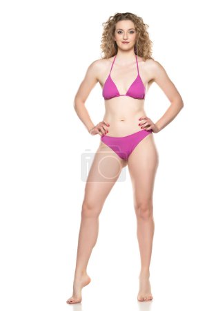Junge blonde Frau im Bikini-Badeanzug steht auf weißem Hintergrund.