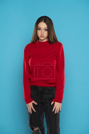 Photo for Cute girl in red blouse and black jeans isolated on blue studio background - Royalty Free Image