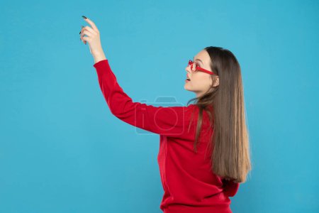 Photo for Young smiling student pointing on a empty blue space - Royalty Free Image