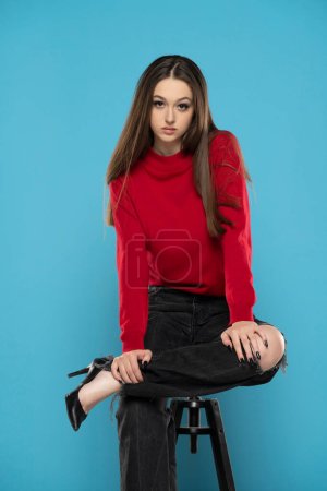 Photo for Cute girl in red blouse and black jeans isolated on blue studio background - Royalty Free Image