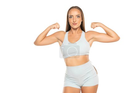 Photo for Young sports woman with long hair in a shorts and top showing biceps on a white studio background - Royalty Free Image