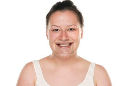 Foto de Retrato de una joven gordita sonriente sin maquillaje sobre un fondo blanco. - Imagen libre de derechos