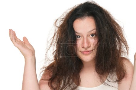 Téléchargez les photos : Portrait d'une jeune femme joufflue aux cheveux longs et désordonnés sur fond de studio blanc. - en image libre de droit