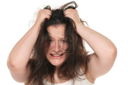 Téléchargez les photos : Portrait d'une jeune femme potelée nerveuse tirant ses longs cheveux sur fond blanc. - en image libre de droit