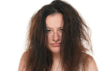 Téléchargez les photos : Portrait d'une jeune femme joufflue aux cheveux longs et désordonnés sur fond blanc. - en image libre de droit