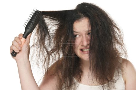 Foto de Retrato de una joven mujer gordita nerviosa que se frota el pelo largo y desordenado sobre un fondo blanco. - Imagen libre de derechos