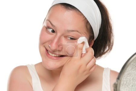 Téléchargez les photos : A young happy chubby woman removing makeup with the wet tissues  on white background. - en image libre de droit