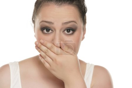 Foto de Regordeta mujer cubriendo su boca porque el mal aliento en un fondo de estudio blanco - Imagen libre de derechos