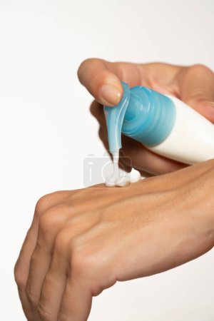 Foto de Woman hands pushing pump plastic body milk bottle on white background with copy space - Imagen libre de derechos