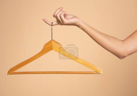 Photo for Woman finger holding empty hanger on a beige studio background. Mock up for design - Royalty Free Image