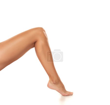Foto de Hermosa pierna de mujer bien arreglada de cerca sobre un fondo blanco aislado, el concepto de depilación del cuidado de la piel del pie o deshacerse de la celulitis. - Imagen libre de derechos